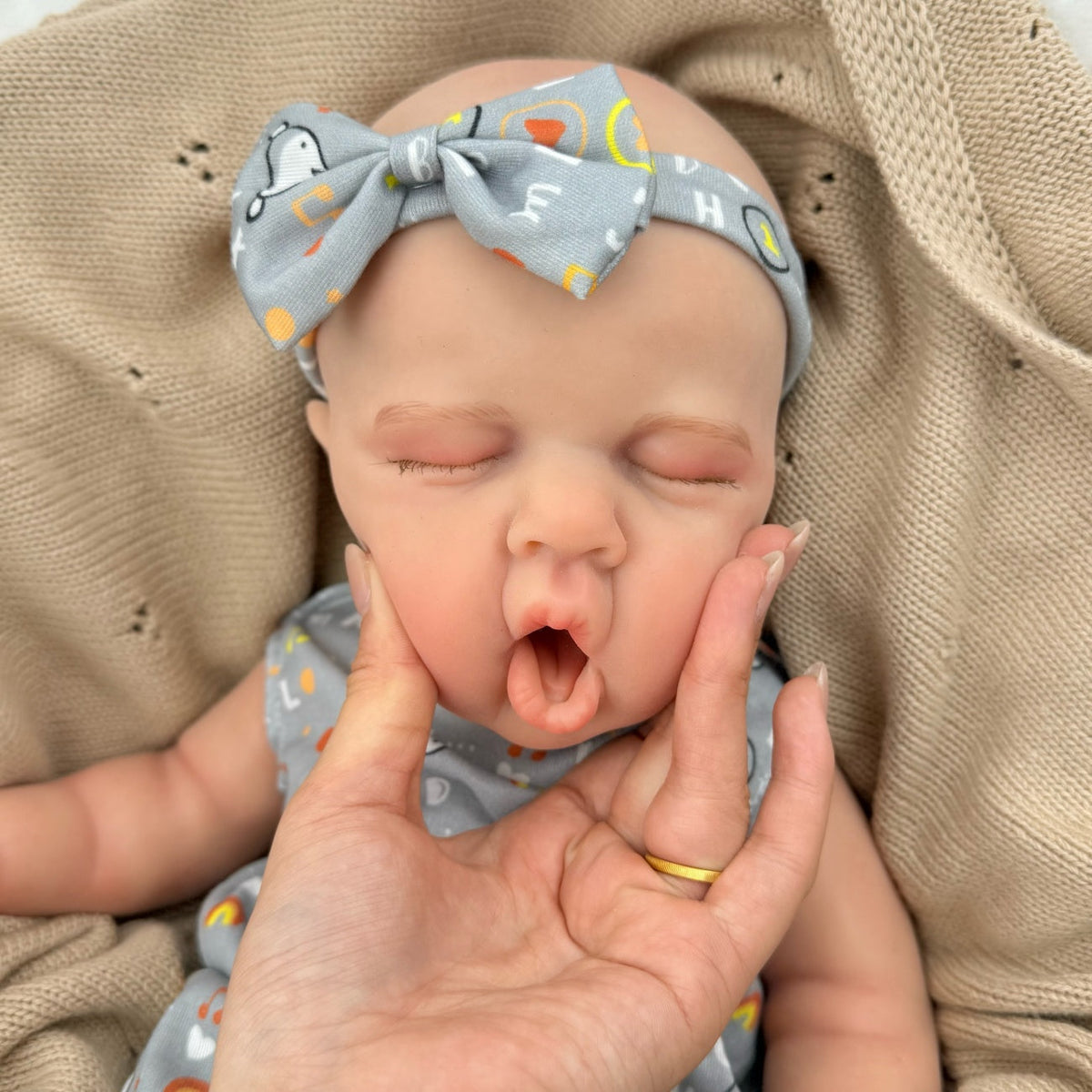 Bambina reborn Loulou addormentata in silicone estensibile alta 45 cm con vestitino grigio a stampa con lettere