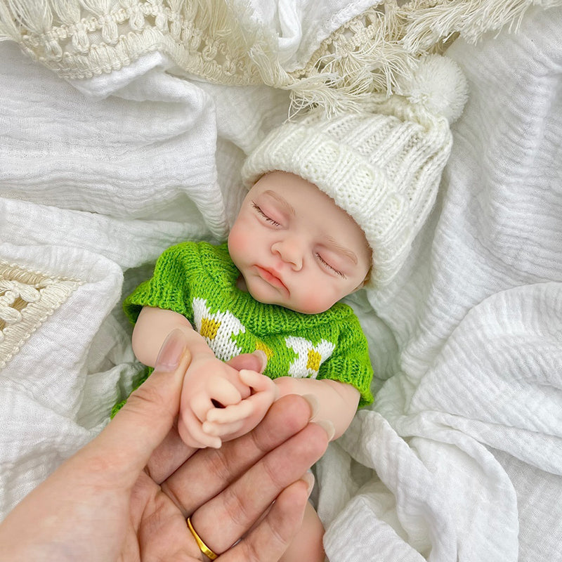 Bambola reborn Irys 30 cm realistica interamente in silicone con occhi chiusi vestita con un maglione verde