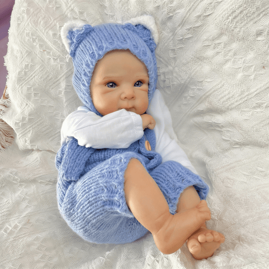 Bambola reborn Bettie da 45cm con occhi azzurri vestita con un body blu lavorato a maglia