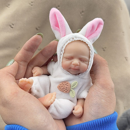 Bambola reborn Pascale Mini in silicone da 15 cm con occhi chiusi vestita da coniglietto bianco