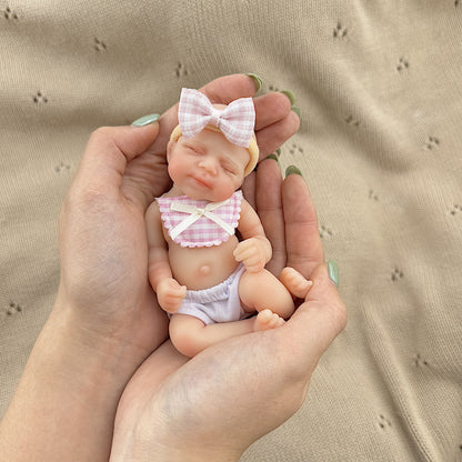 Bambola reborn Pascale in silicone da 15 cm con occhi chiusi e bavaglino a quadri rosa