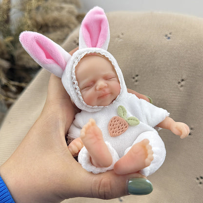 Bambola reborn Pascale Mini in silicone da 15 cm con occhi chiusi vestita da coniglietto bianco