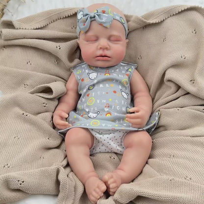 Bambina reborn Loulou addormentata in silicone estensibile alta 45 cm con vestitino grigio a stampa con lettere