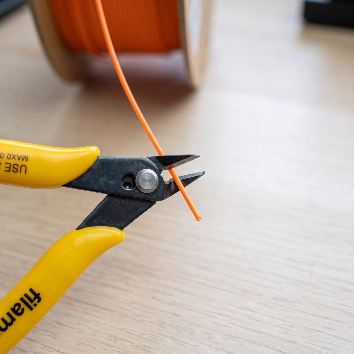 Filamentor zijkniptang knipt oranje filament rechtstreeks van de spoel
